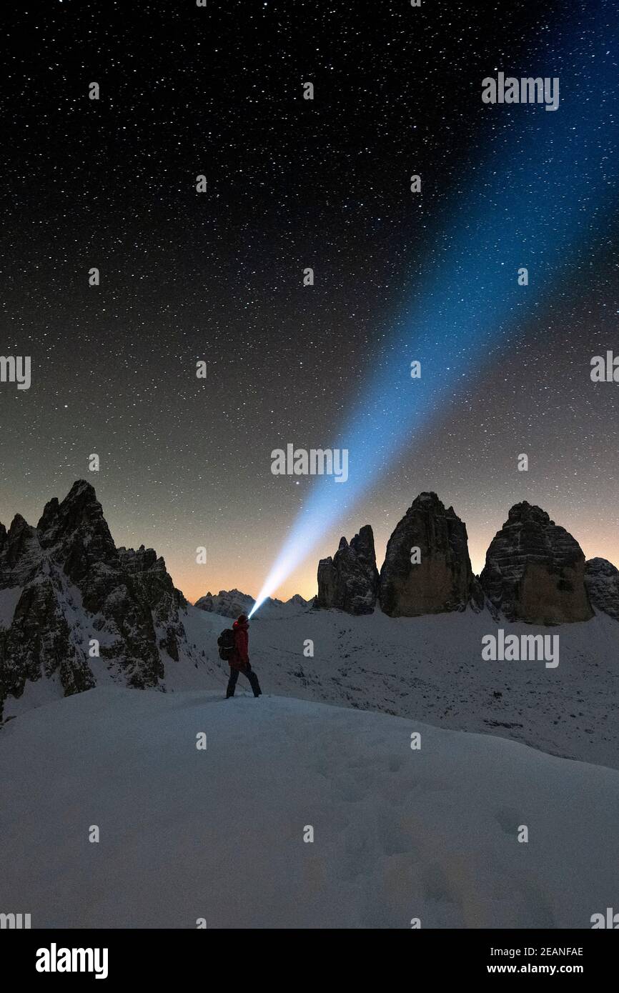 Hiker with head torch admiring stars on Monte Paterno and Tre Cime di Lavaredo, Sesto Dolomites, South Tyrol, Italy, Europe Stock Photo