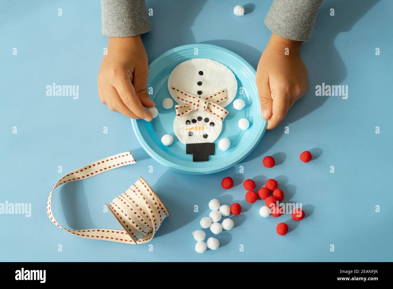 Hands of child creating a snowman with ribbon and pompom at Christmas time, Italy, Europe Stock Photo