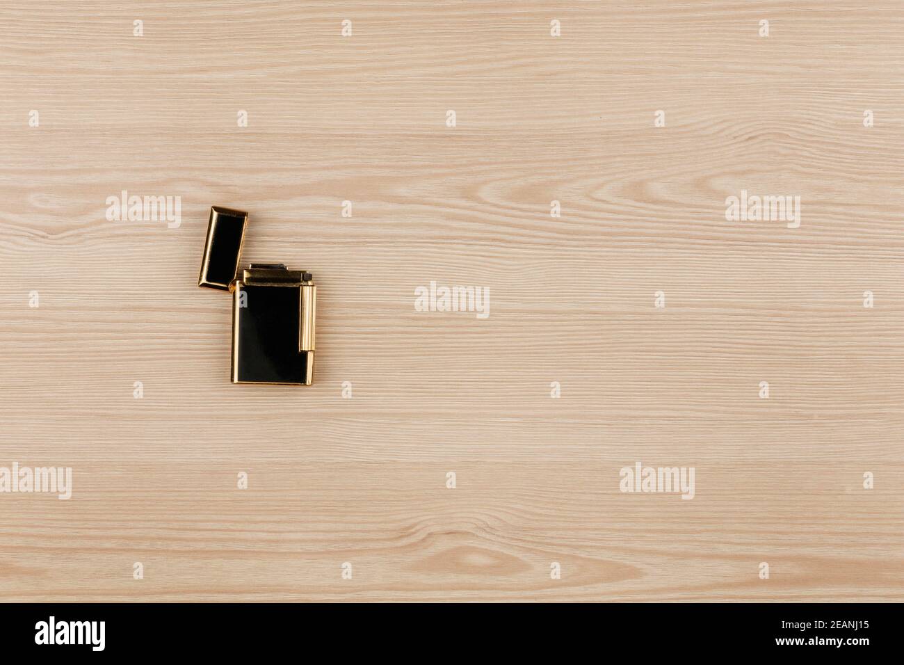 Luxury gold lighter lying on a wooden surface. With room for your text. Stock Photo