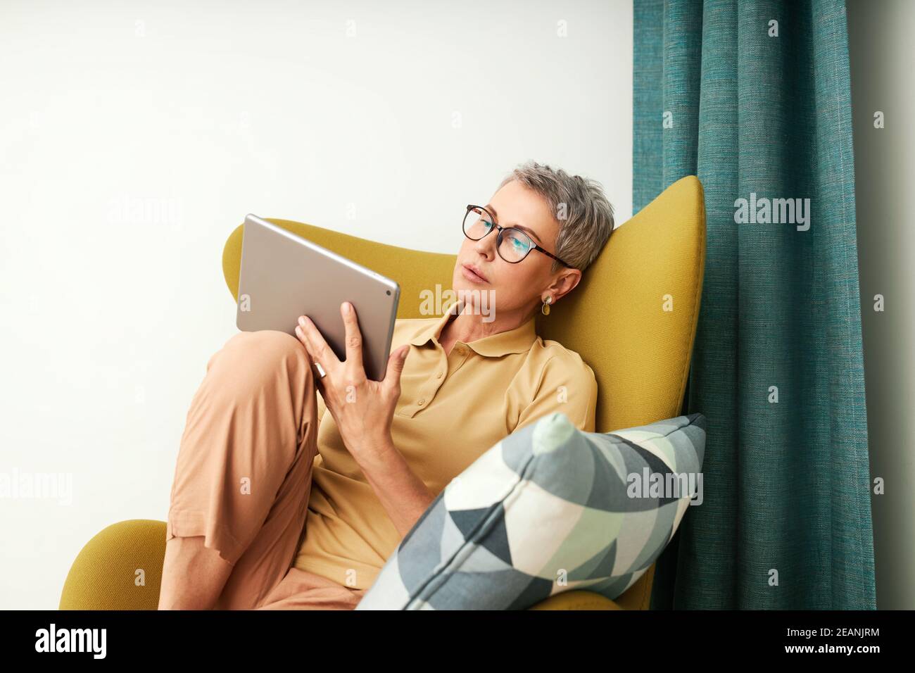 Mature woman sitting on armchair at home Stock Photo - Alamy