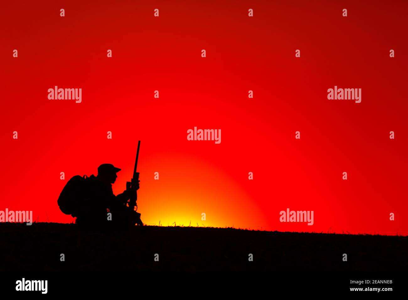 Sniper, hunter siting on hill with rifle on sunset Stock Photo