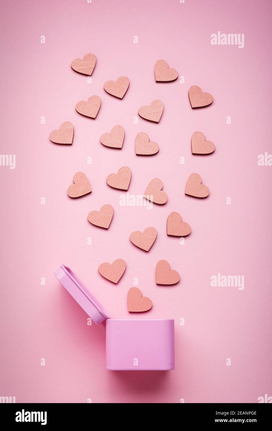 Lots of pink stuff. Pink metal gift box and decorative wooden hearts on pink background. Stock Photo