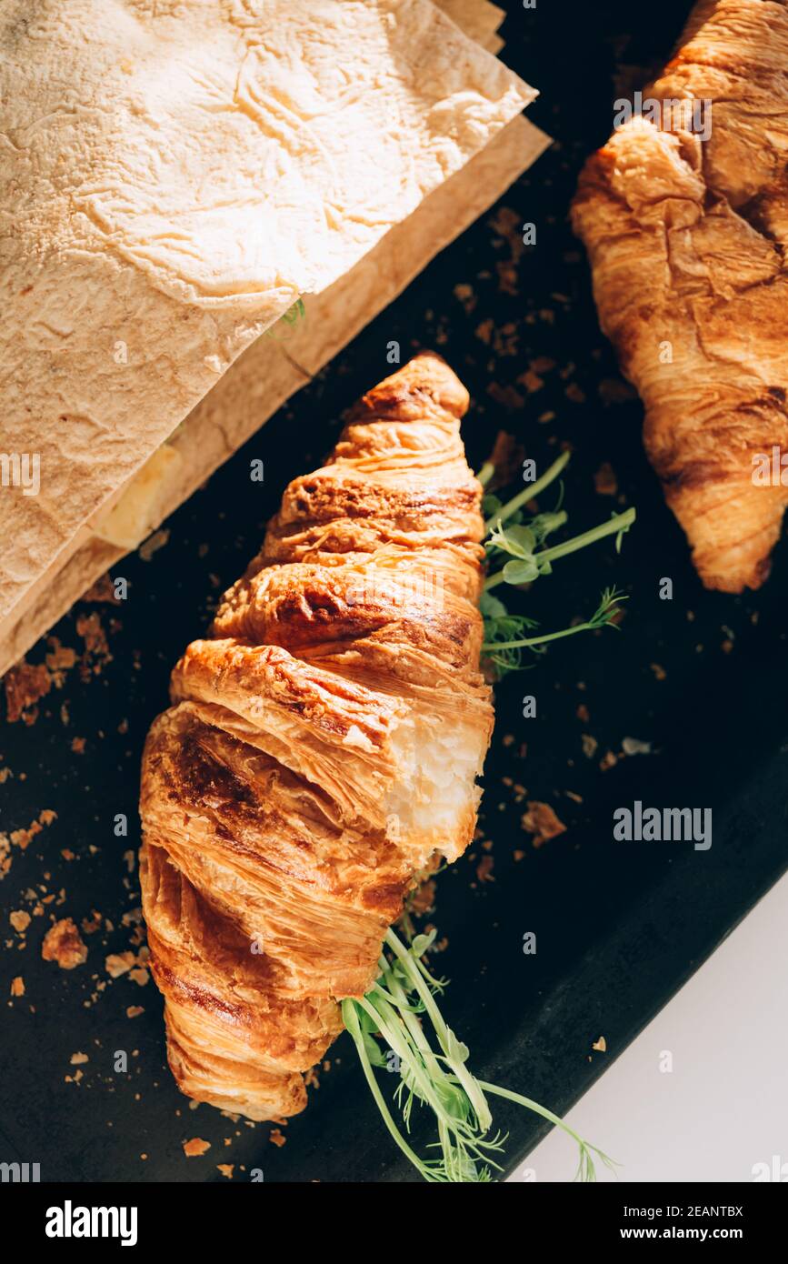 Delicious fresh baked Croissant and pita with cheese, microgreen sprouts in bakery black pan