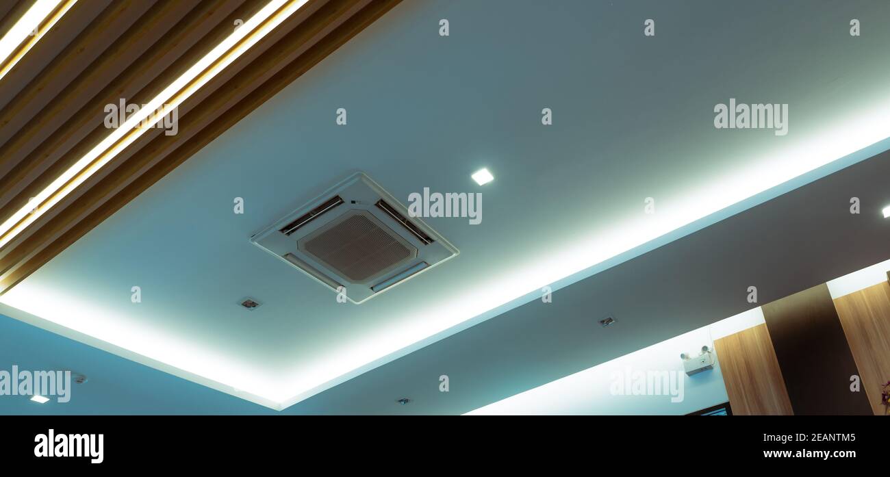 Selective focus on cassette type air conditioner mounted on ceiling wall. Air duct on ceiling in hotel. Air heading unit on gypsum wall. Cool system in the building. Air flow and ventilation system. Stock Photo