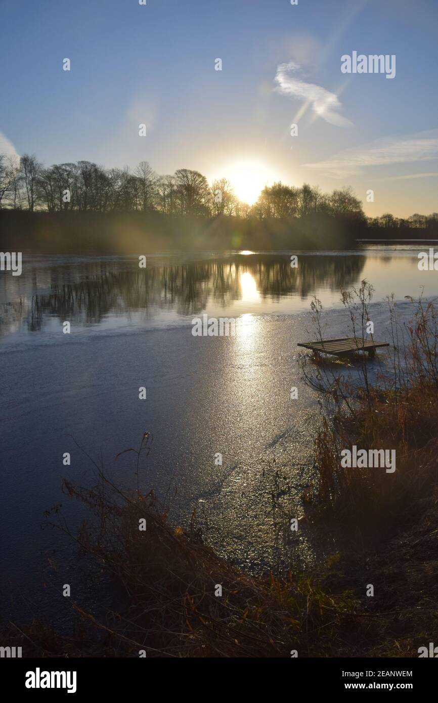 Winter sunrise across a lake surface highlighting the frozen ice patterns on the water. Stock Photo