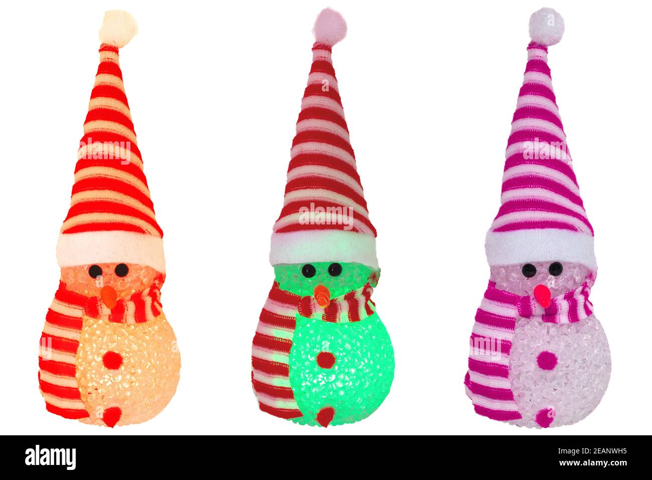 Christmas decoration elements isolated. Close-up of three various colored illuminated happy cute winter snowman with red white striped hat and scarf isolated on a white background. Macro photograph. Stock Photo