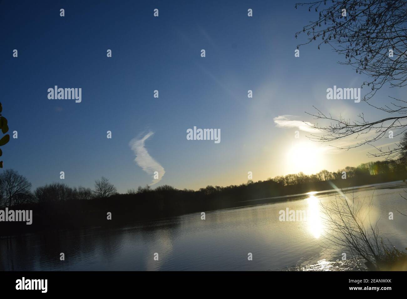 Winter sunrise across a lake surface highlighting the frozen ice patterns on the water. Stock Photo