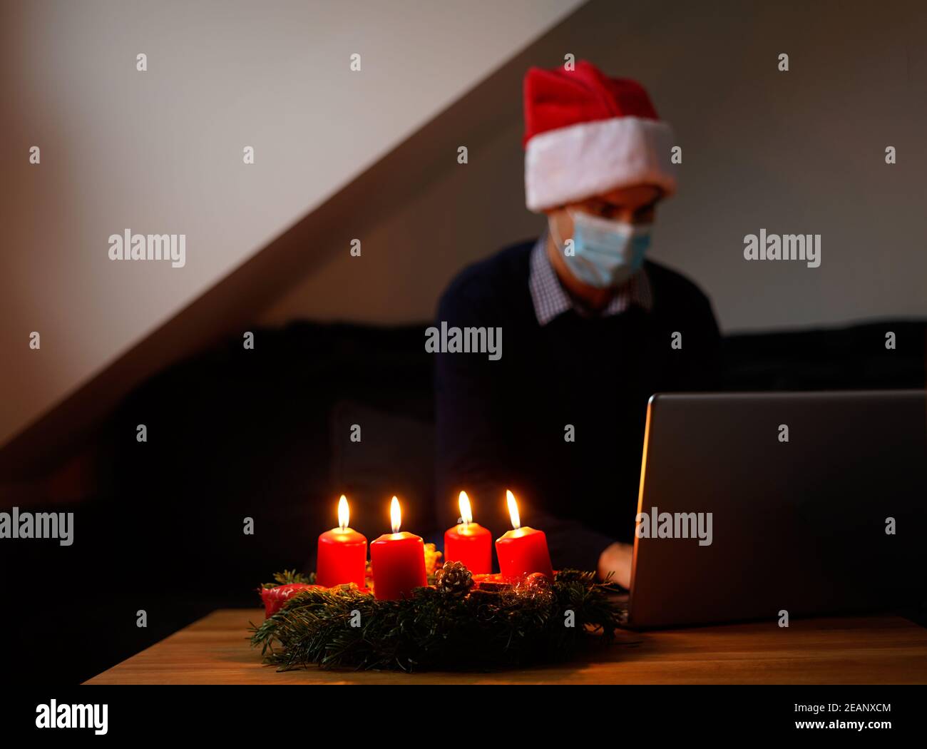 social distance christmas concept. christmas with corona virus online and alone. young man with medical face mask and santa hat Stock Photo