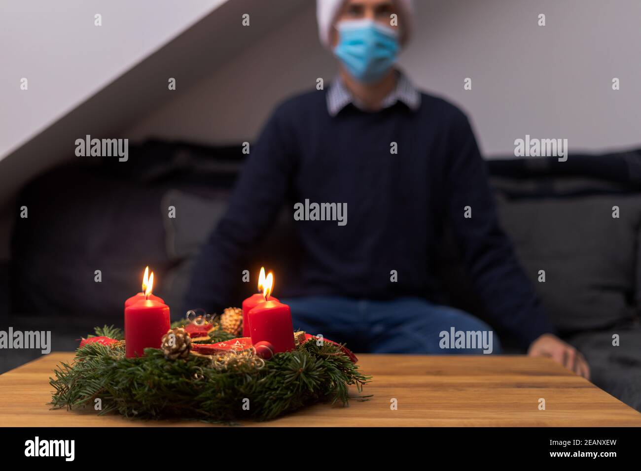 social distance christmas concept. christmas with corona virus online and alone. young man with medical face mask and santa hat Stock Photo