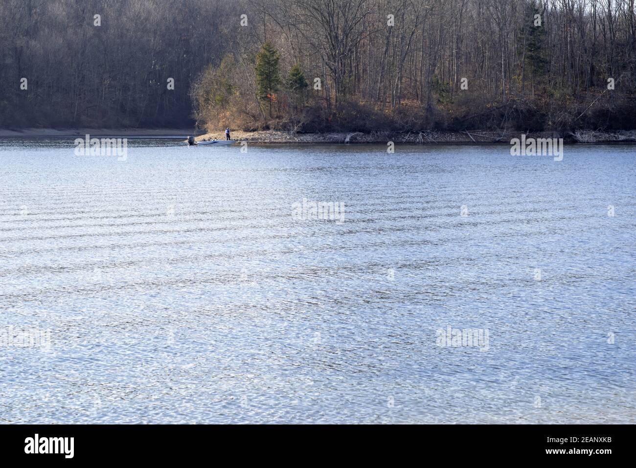 Lone person and a boat across a Autumn lake Stock Photo