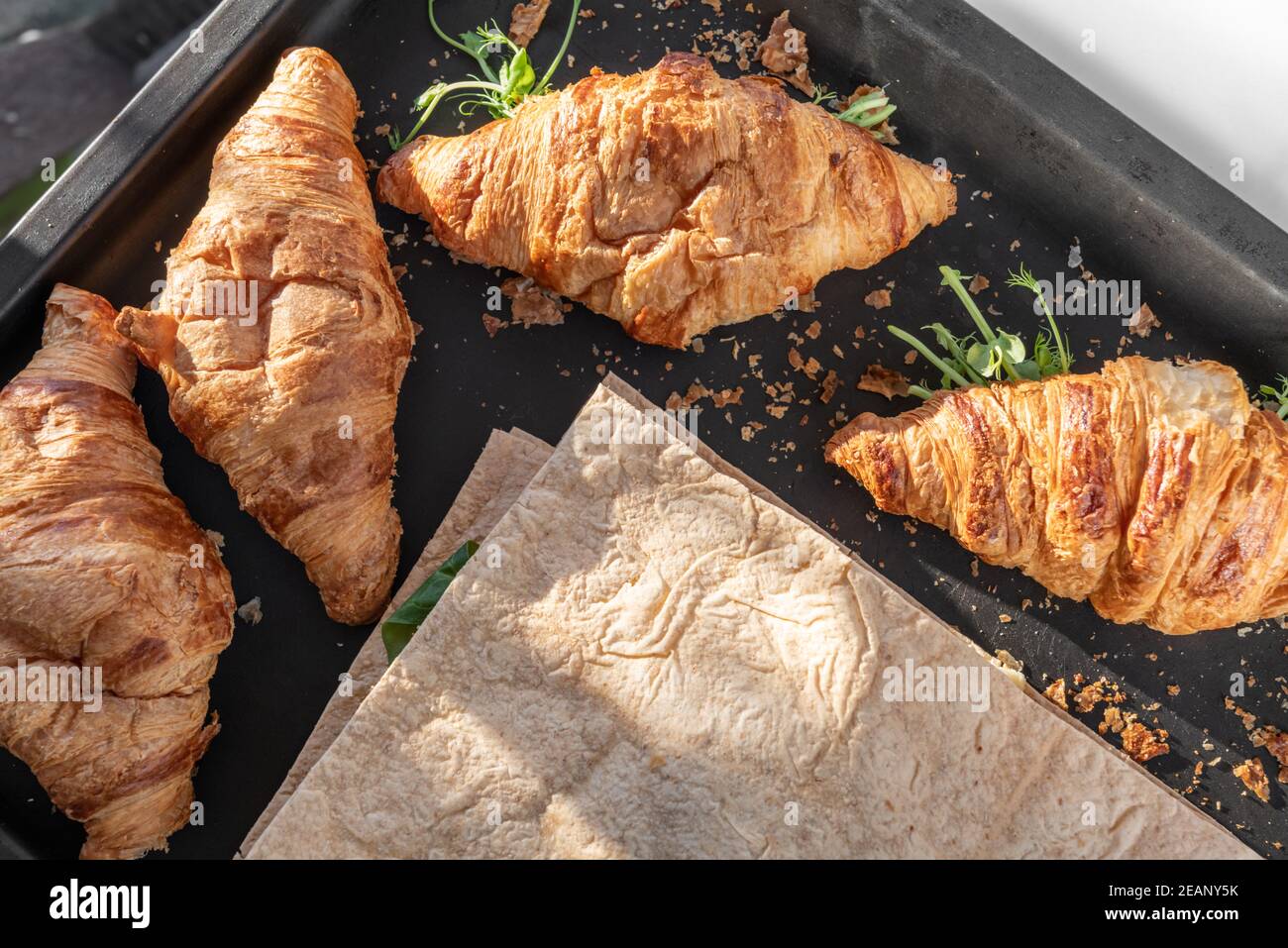 Delicious fresh baked Croissant and pita with cheese, microgreen sprouts in bakery black pan