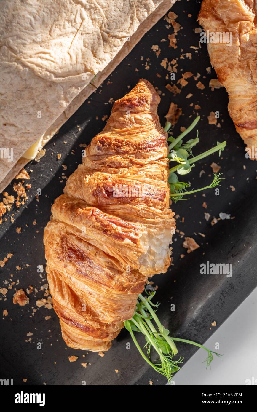 Delicious fresh baked Croissant and pita with cheese, microgreen sprouts in bakery black pan