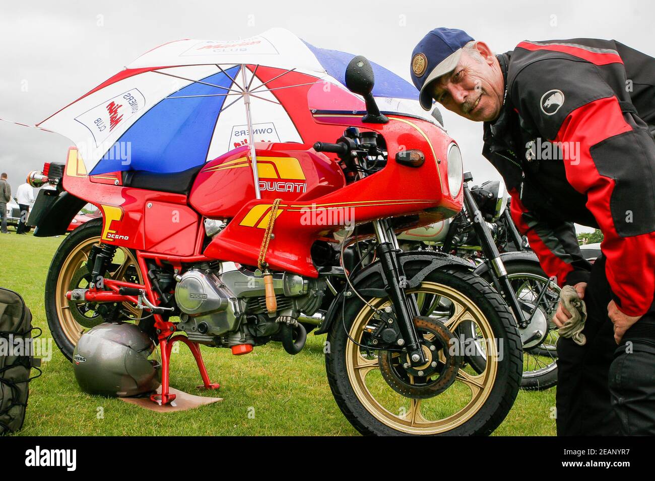 Proud owner of red Ducati motorbike exhibiting at a classic car show, UK Stock Photo