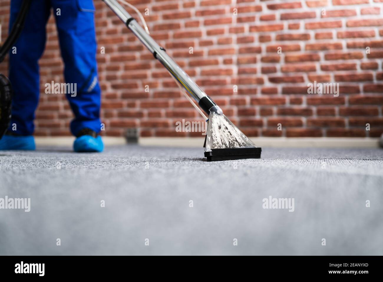 Janitor Cleaning Carpet With Vacuum Cleaner Stock Photo