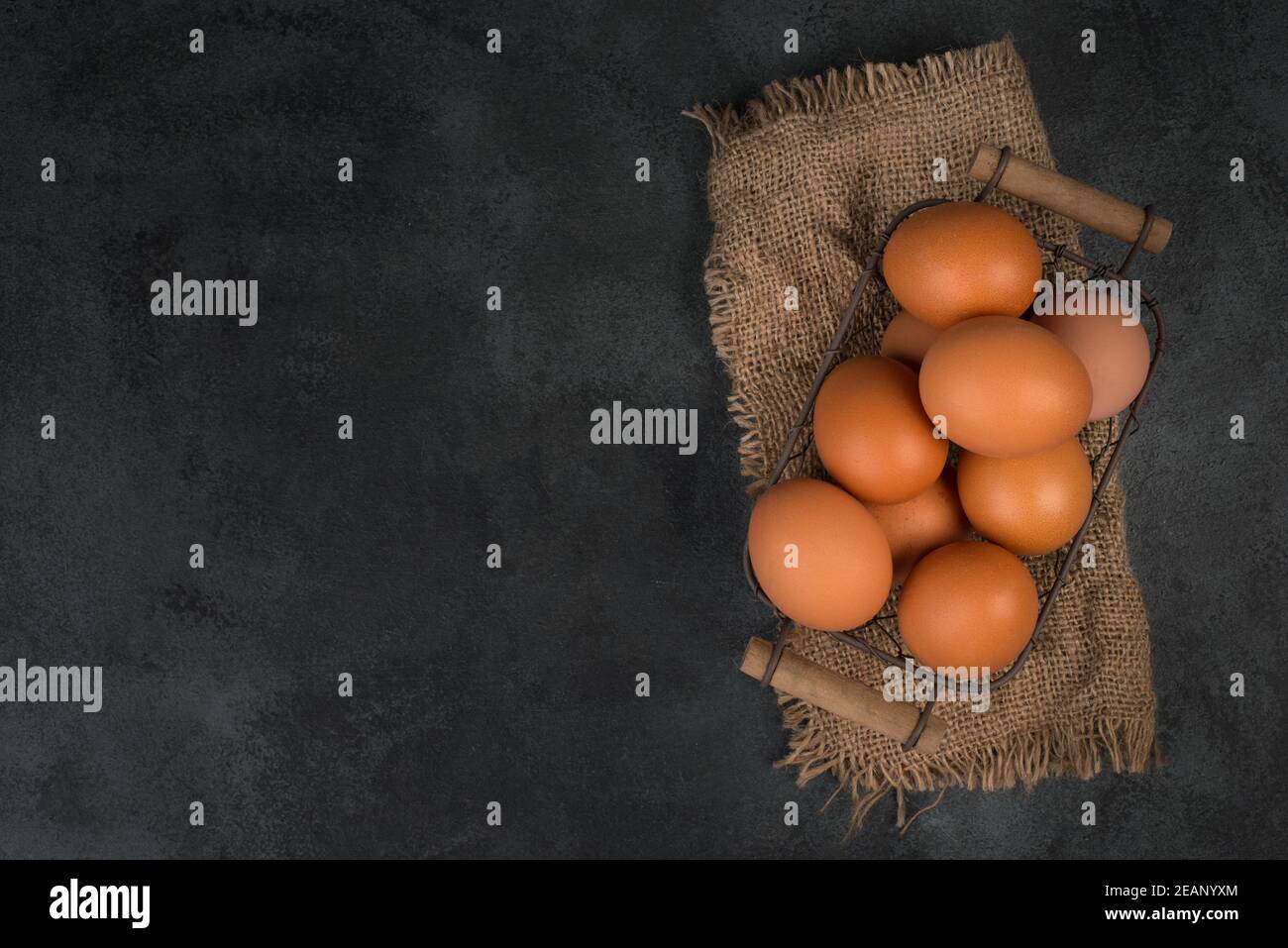 Brown raw chicken eggs in a wooden basket on a grey textured background ...