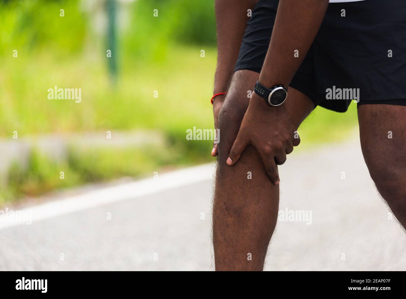 sport runner black man wear watch hands joint hold knee pain Stock Photo