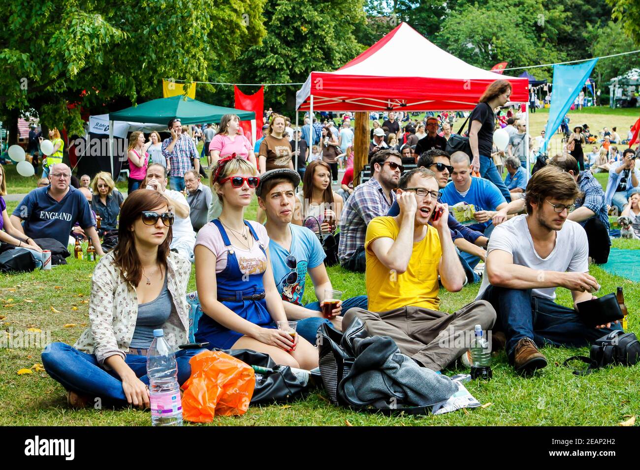 Group of friends sitting on the grass watching a live show at Underground Festival in Crystal Palace,South London Stock Photo
