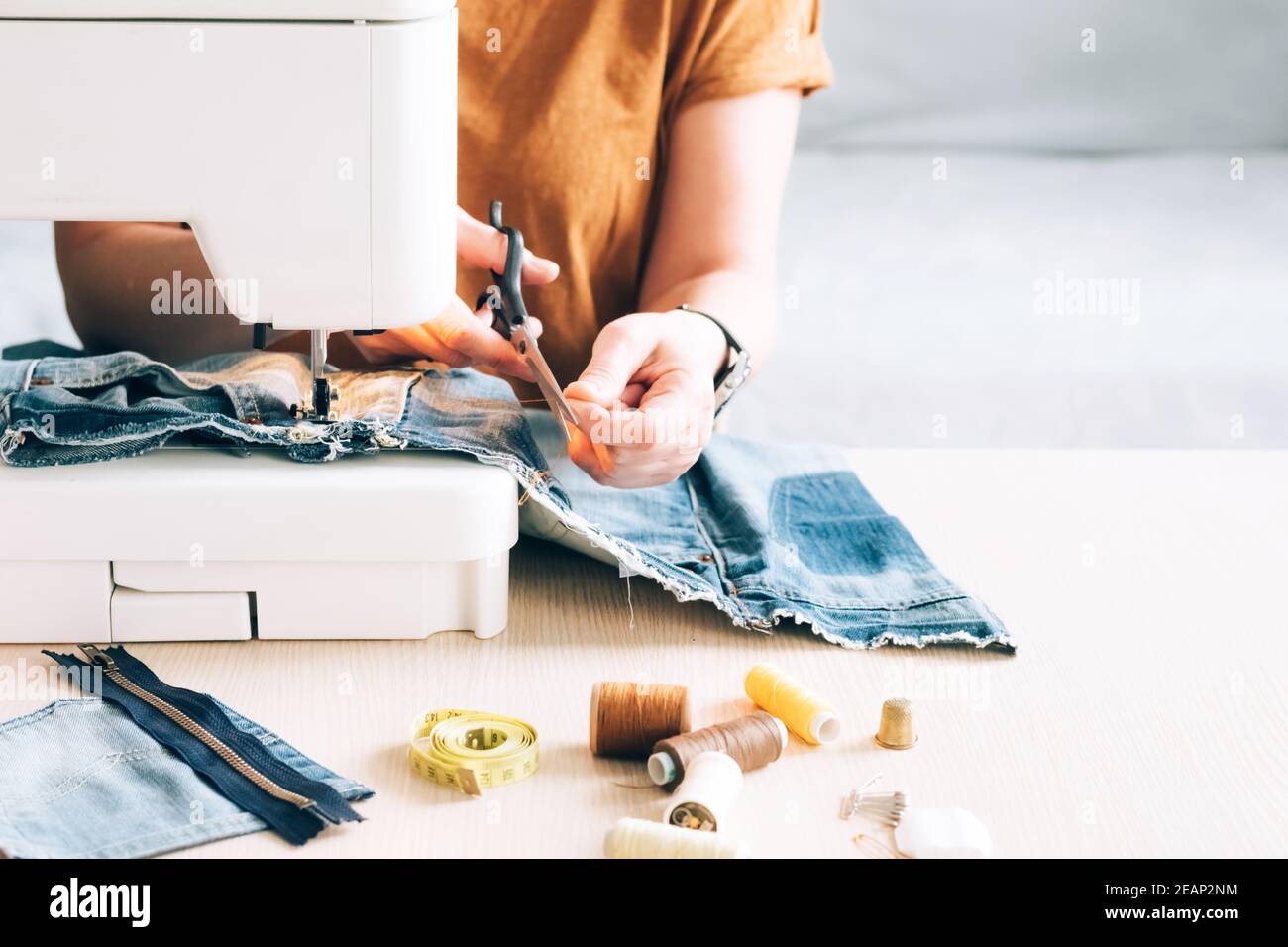 A woman tailor works at a sewing machine sews reuses fabric from old