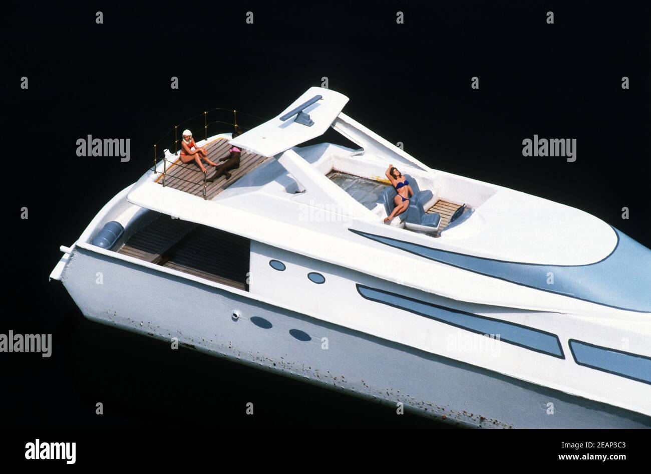Model boat with swimsuit clad sunbathers Stock Photo