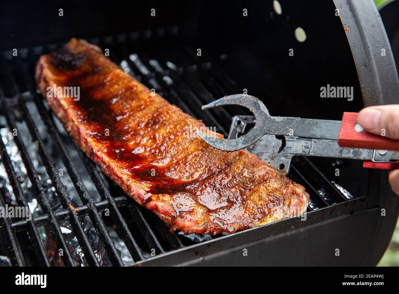 Close-up Of BBQ Roast and Smoked Pork Spareribs glazed with sauze On The Hot Charcoal Grill With Flames, Barbecue and hobby concept Stock Photo