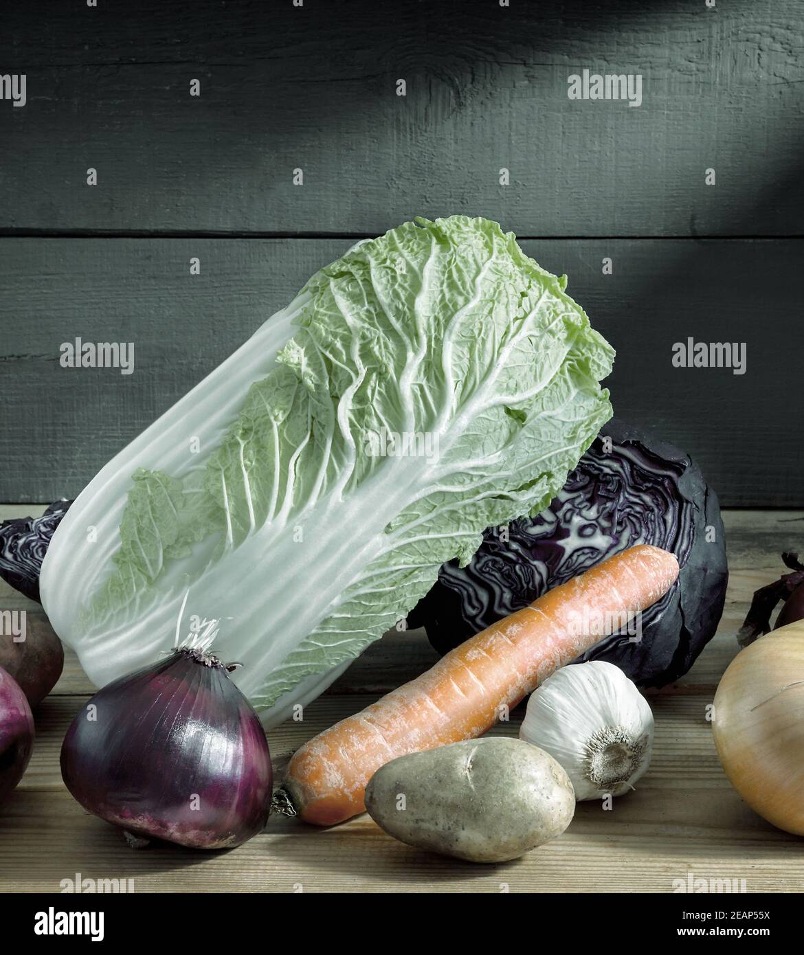 Still life: on a wooden shelf in the basement lies carrots, onions, red and white cabbage. Front view, copy space Stock Photo