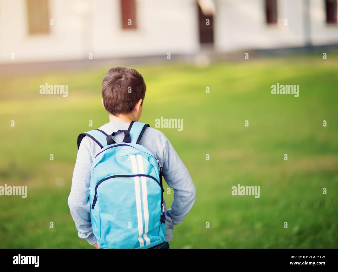 Boy with rucksack infront of a school building Stock Photo