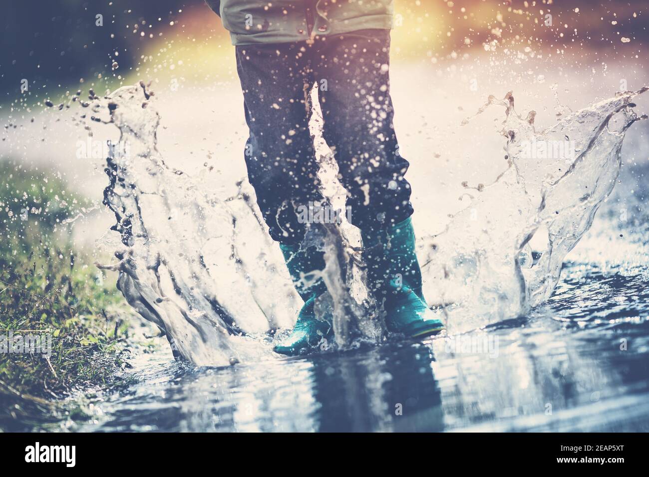 Child walking in wellies in puddle on rainy weather Stock Photo