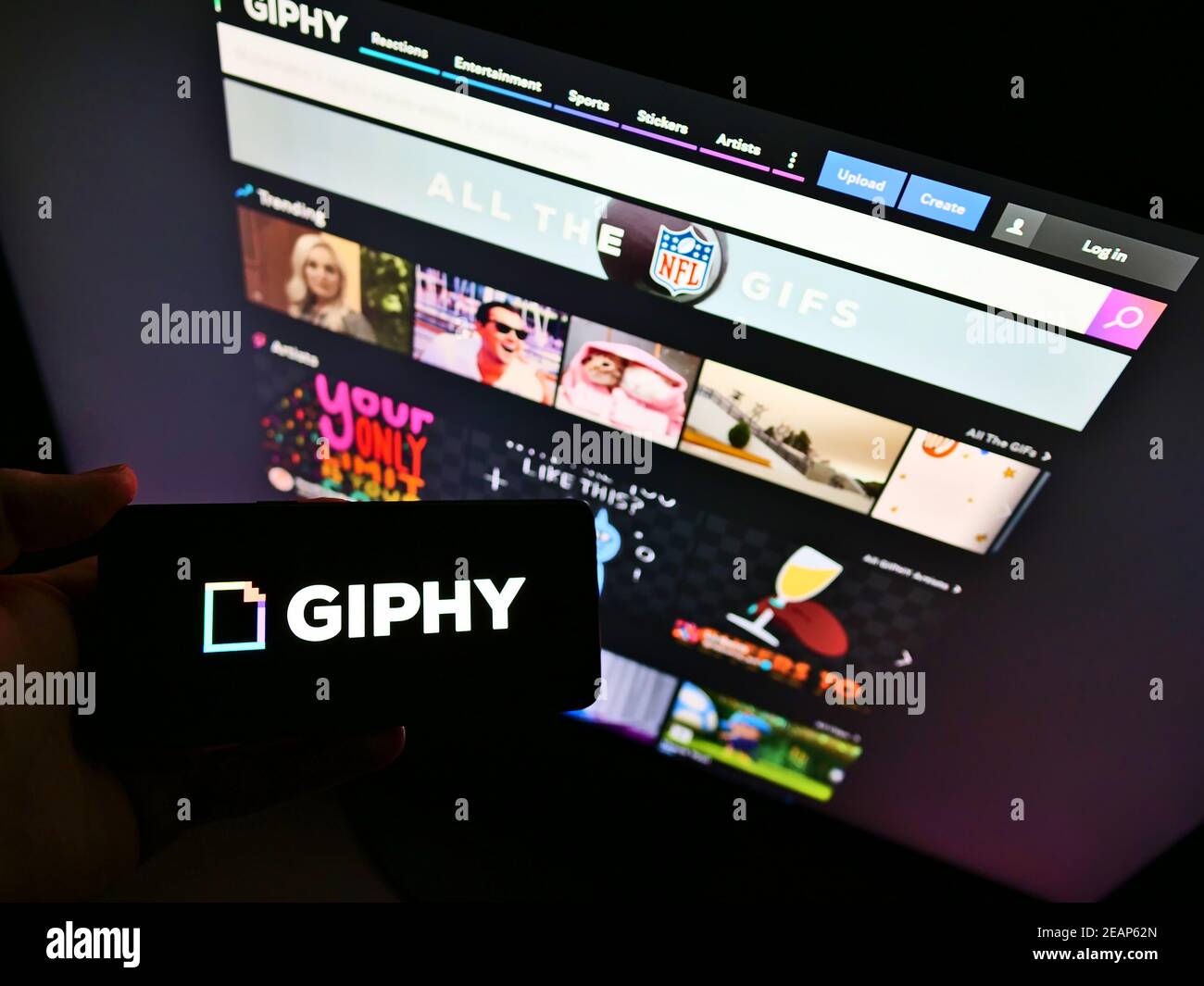 Person holding smartphone with company logo of American online database (GIF files) Giphy Inc. in front of website. Focus on phone display. Stock Photo