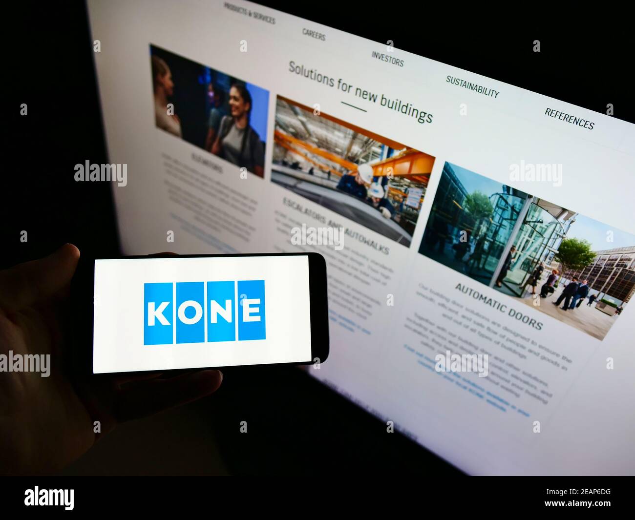 Person holding mobile phone with business logo of Finnish engineering and services company KONE Oyj in front of web page. Focus on cellphone display. Stock Photo