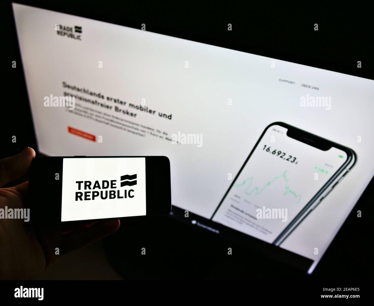 Person holding smartphone with logo of German online broker Trade Republic Bank GmbH on screen in front of website. Focus on phone display. Stock Photo
