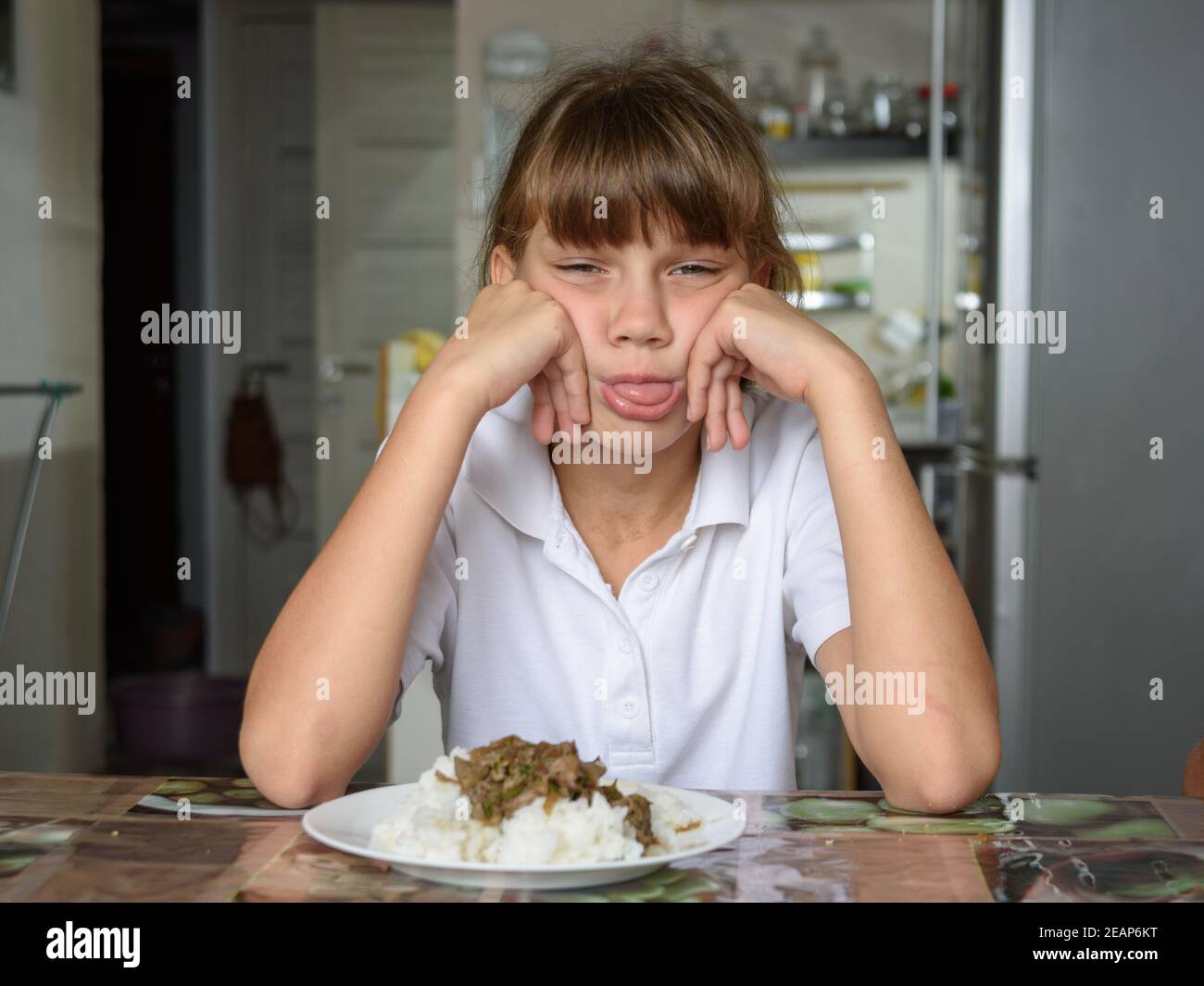 The girl refuses the food offered and shows her tongue Stock Photo