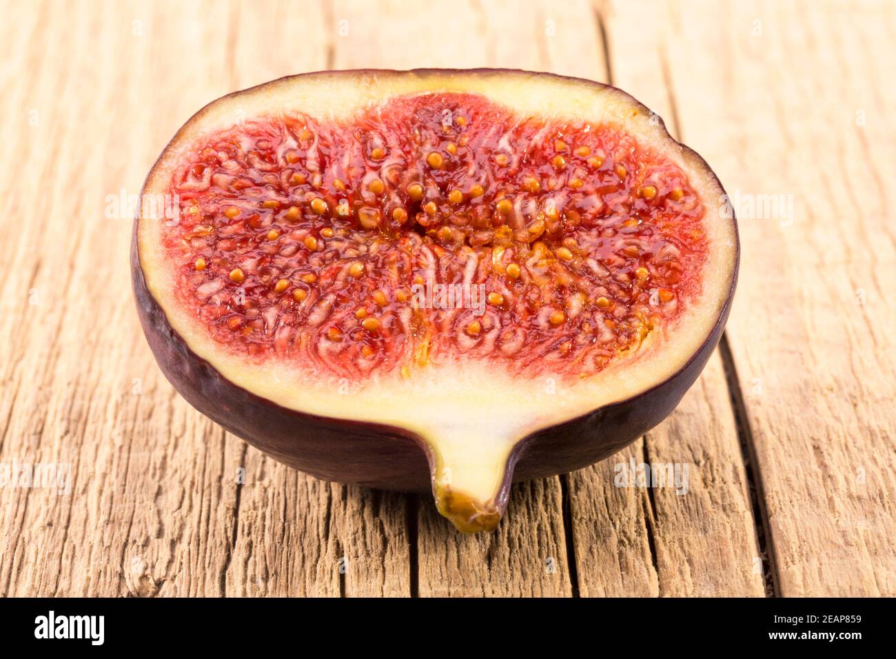 Half of fresh fig on wooden plank, close up. Food photo Stock Photo