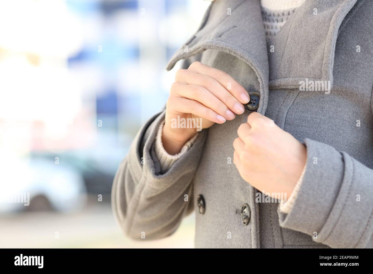 Woman hands fastening button of jacket in winter in the street Stock Photo