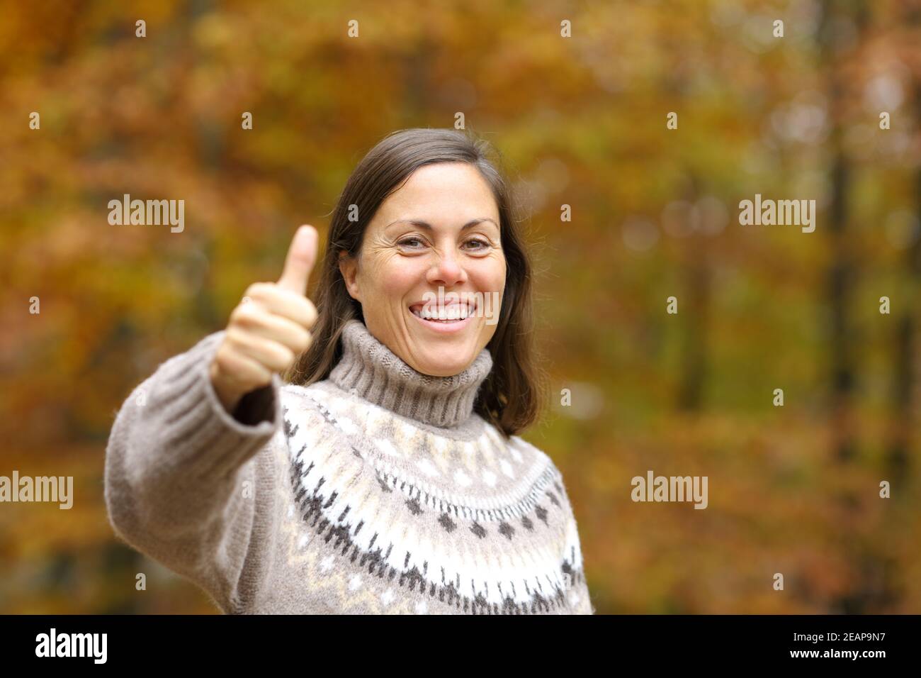 Happy adult woman gesturing thumbs up in autumn Stock Photo