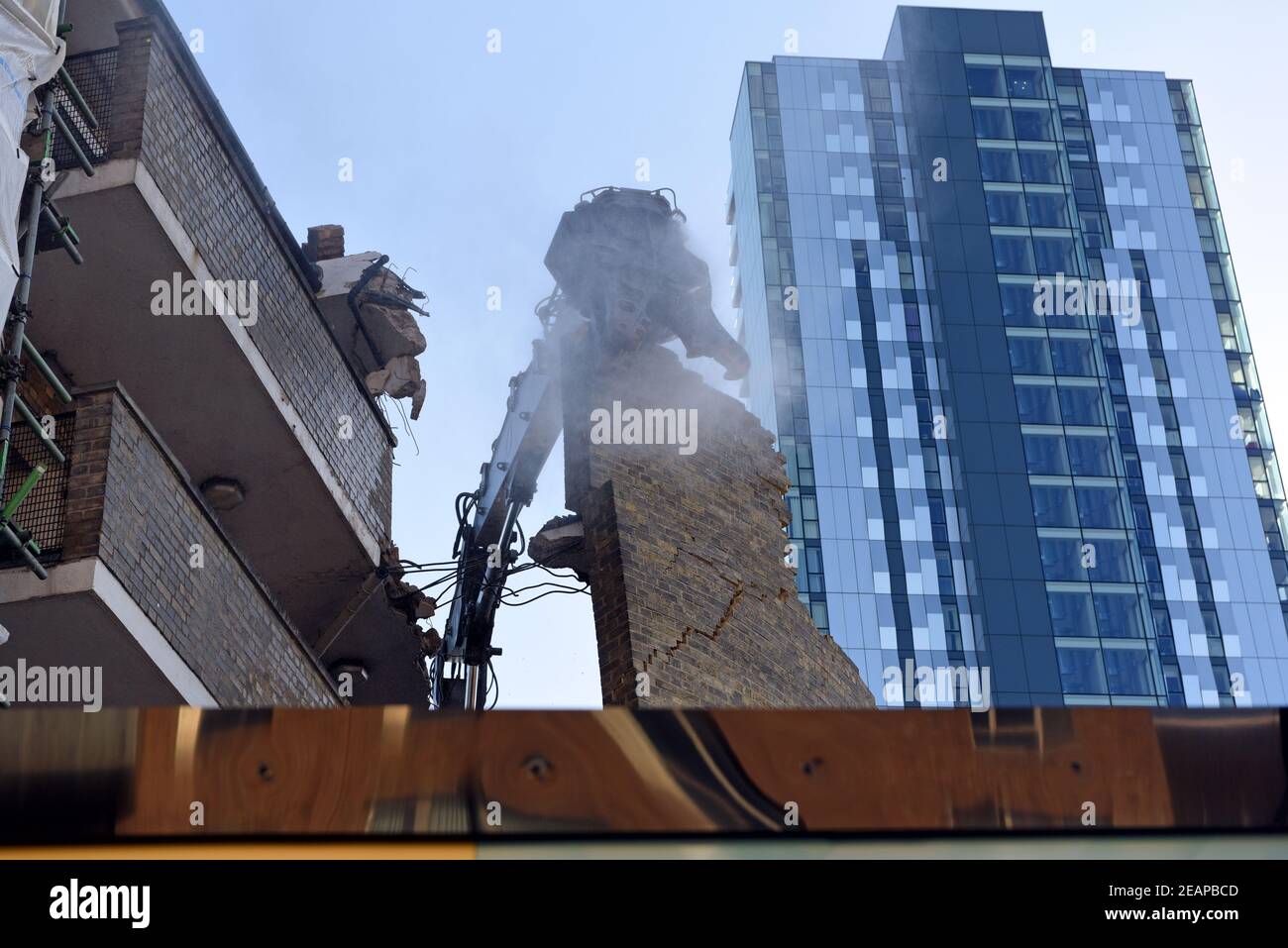 Urban regeneration. A Volvo EC380EHR high reach excavator is used to demolish brick built apartment buildings. Making way for high rise glass towers. Stock Photo
