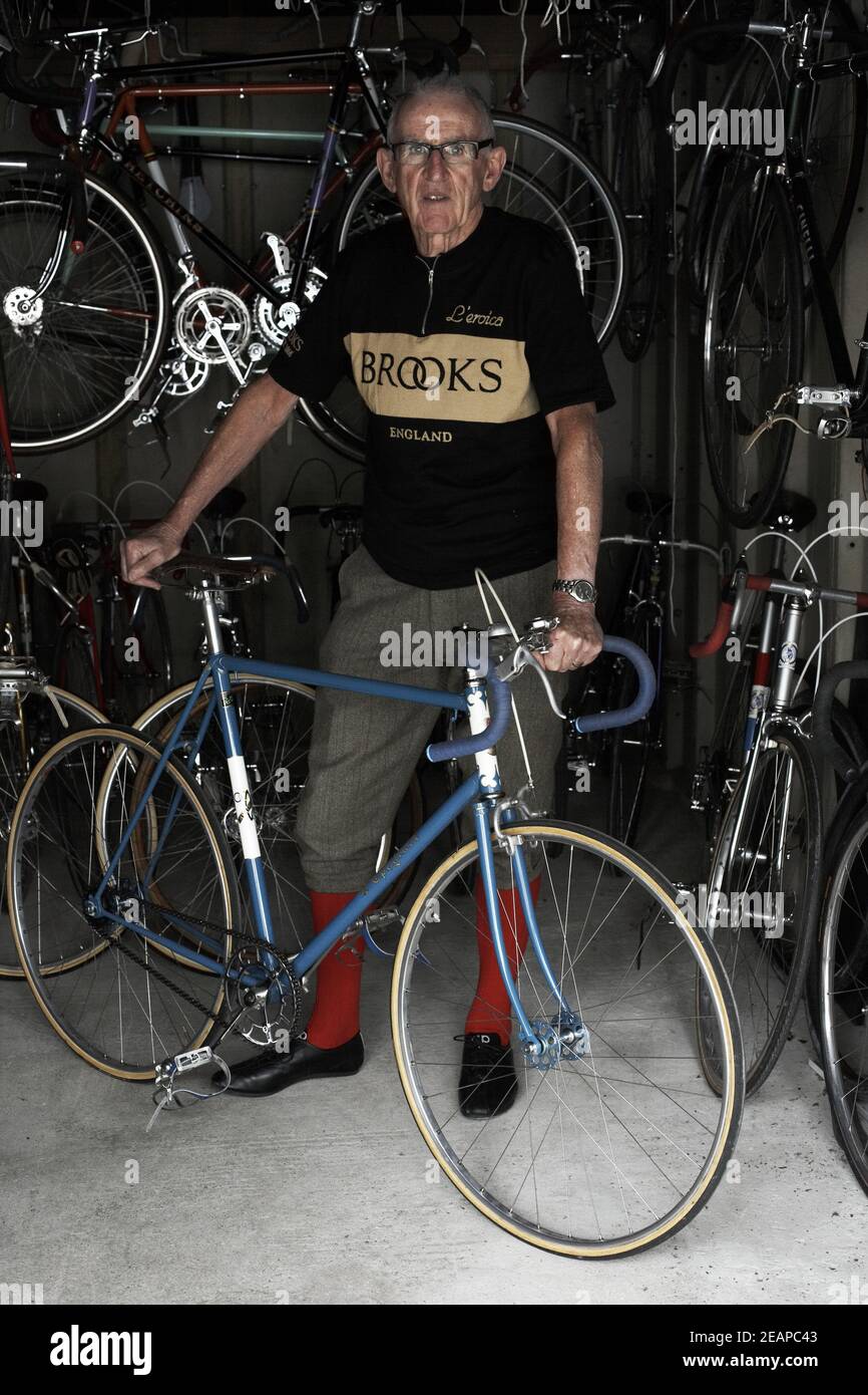 A cyclist stands next to his vintage road race bicycle in a garage. Stock Photo