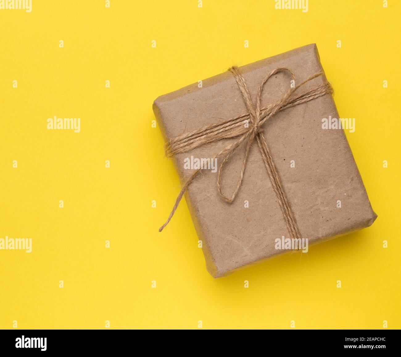 square box with a gift wrapped in brown paper and tied with a brown ro Stock Photo