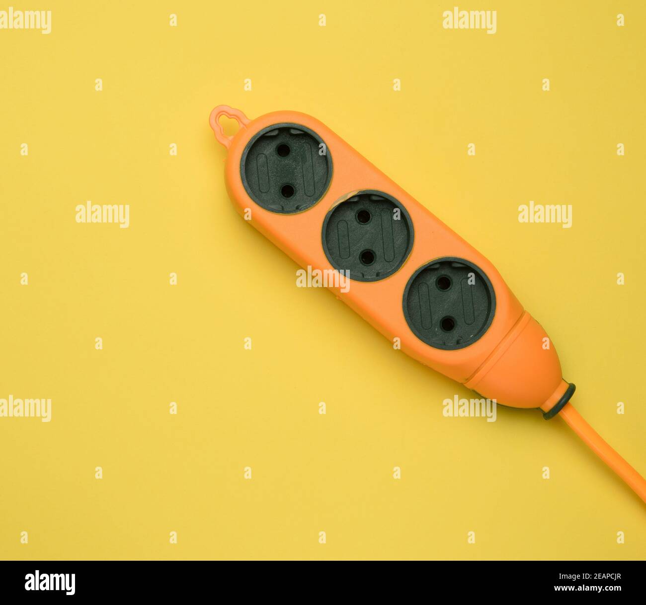 rubber orange power strip with three sockets isolated on a yellow background Stock Photo