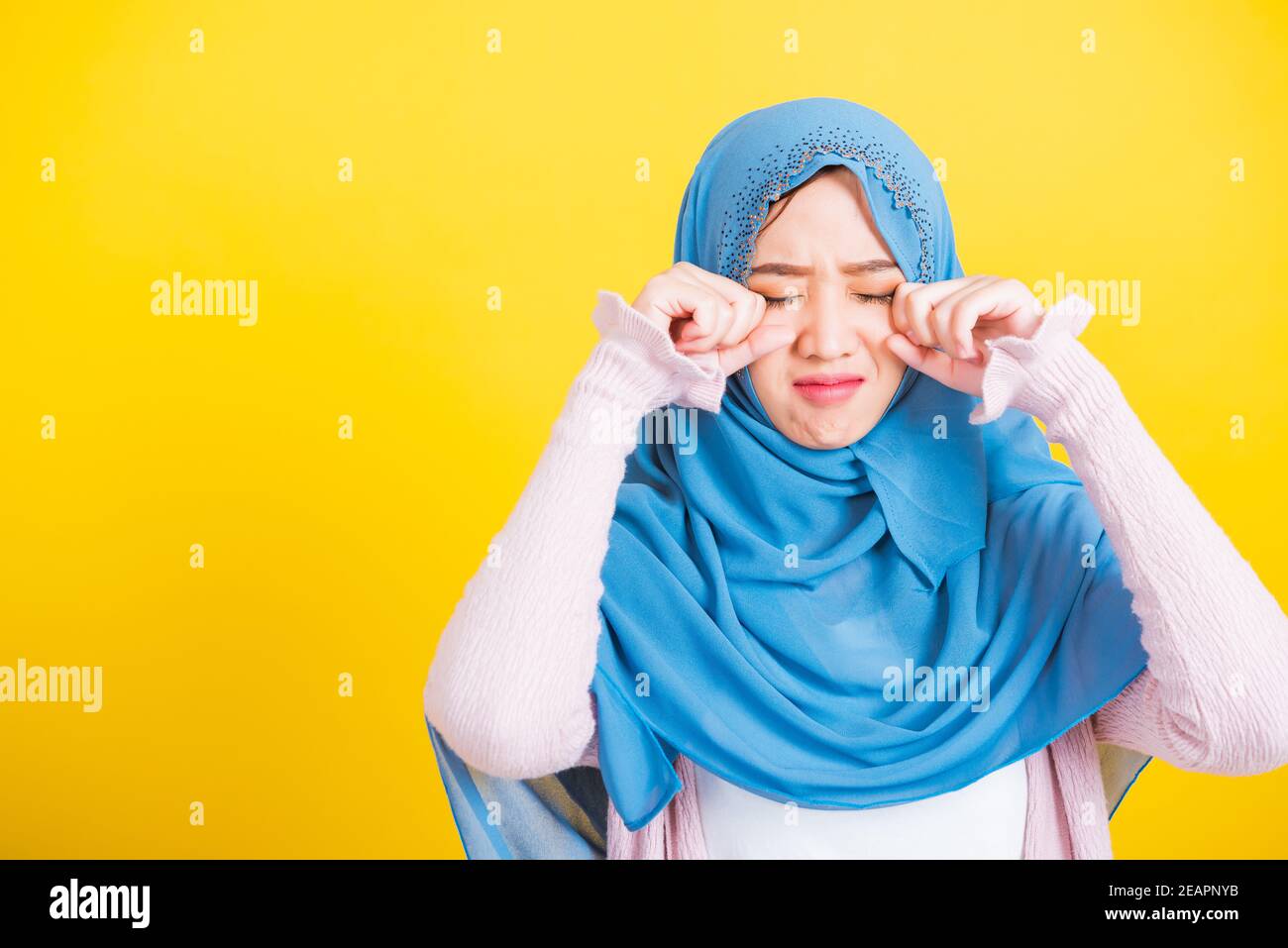Woman wear veil hijab she sad crying using hand wiping tears in her eyes Stock Photo
