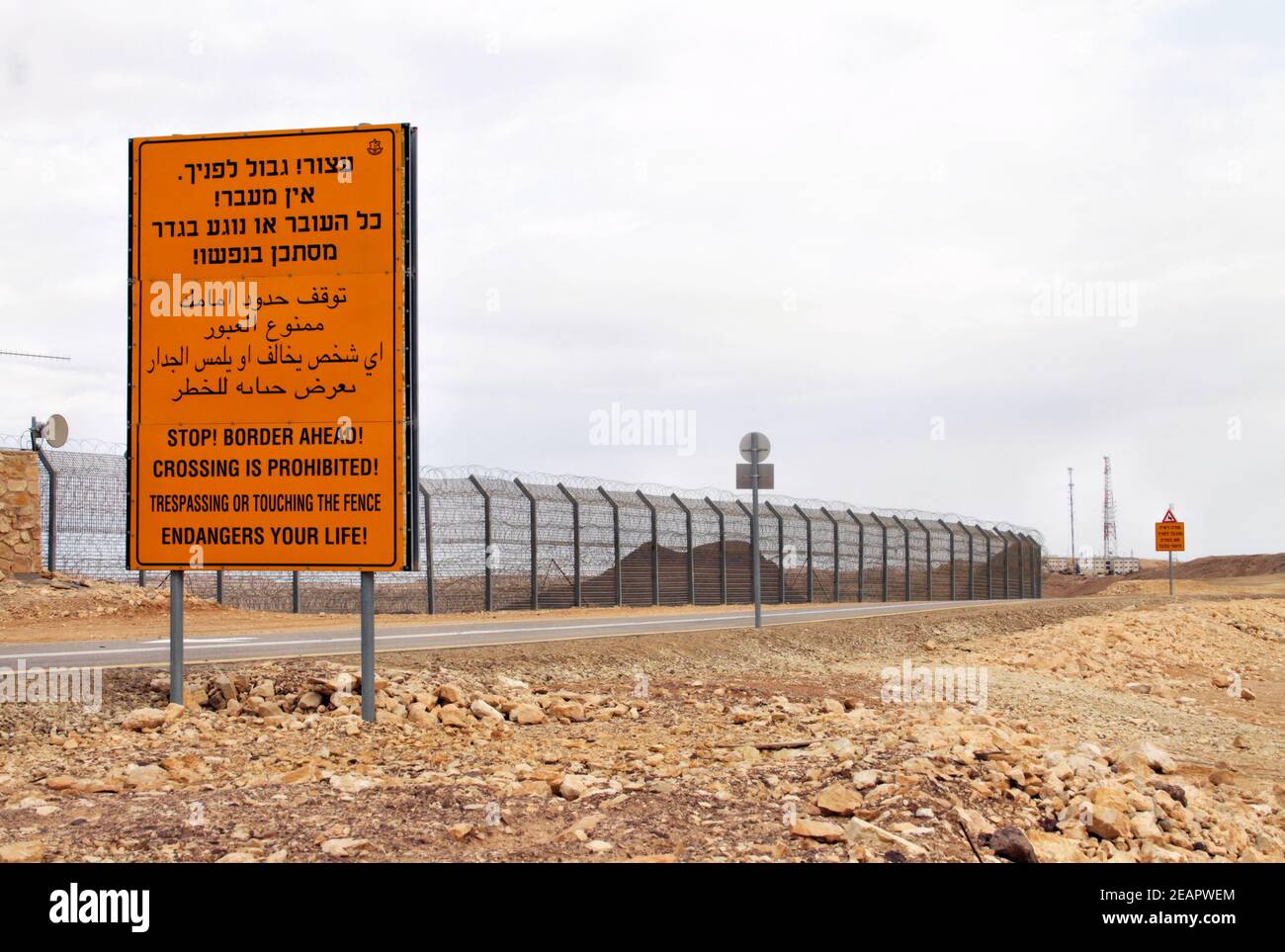 A yellow warning sign sits next to the border fence between Israel and Egypt along Israel's Highway 12 just north of Eilat. Stock Photo