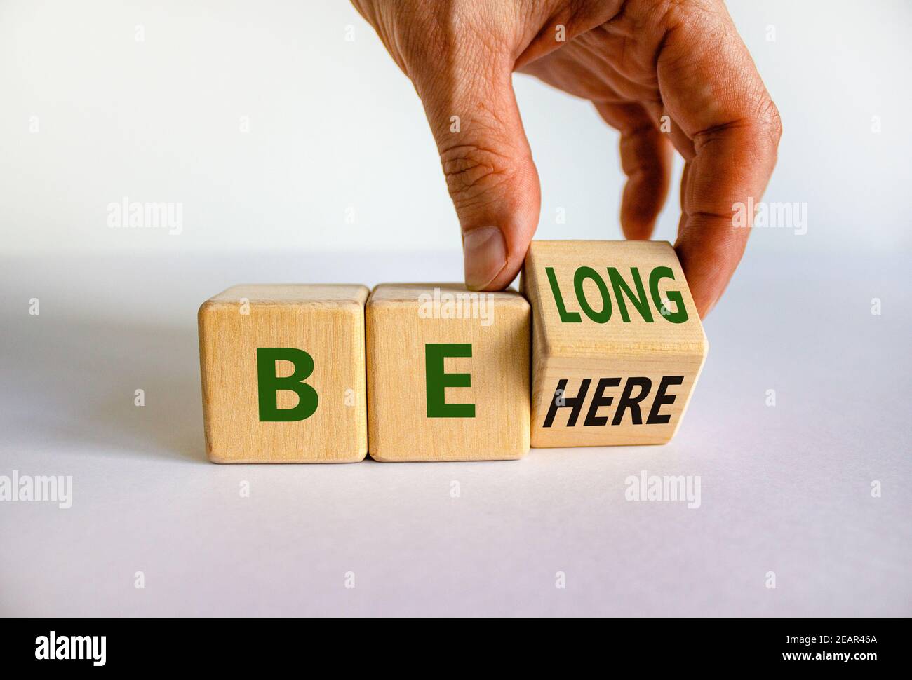 Be here belong symbol. Businessman hand turns a cube and changes words 'be here' to 'belong