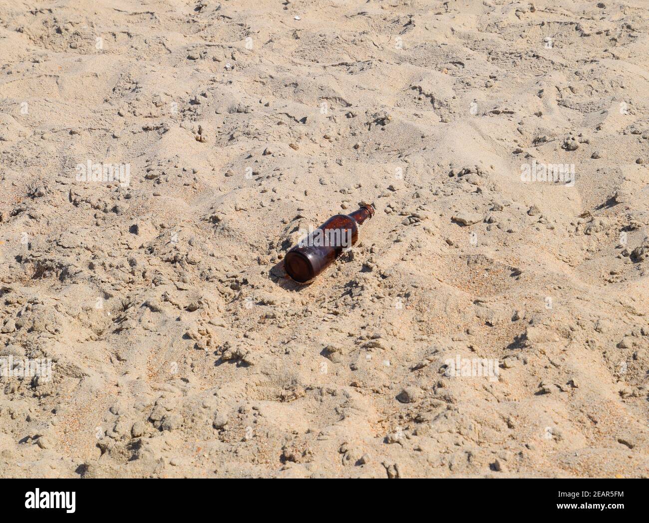 An empty bottle of beer is lying on the sand Stock Photo