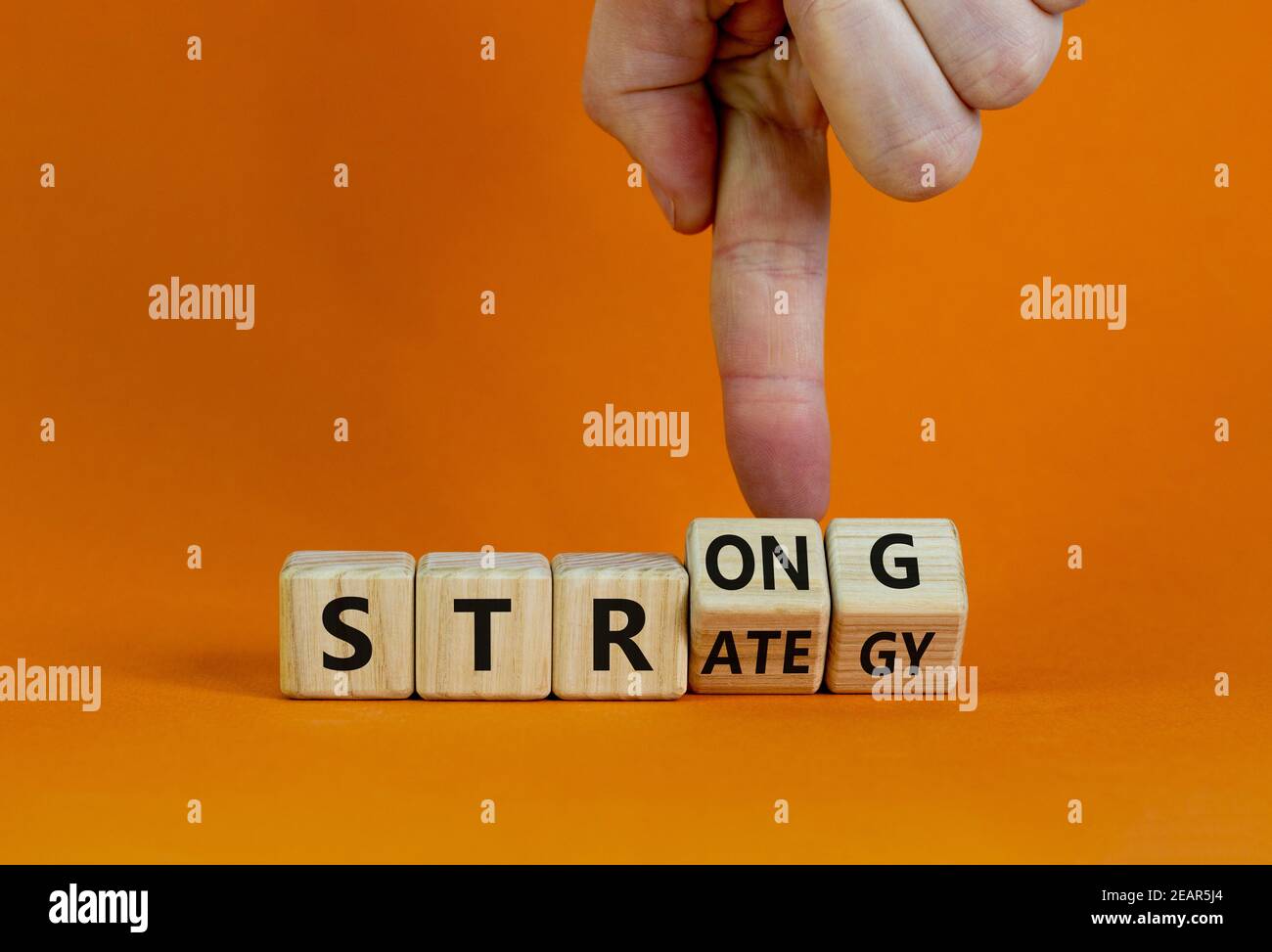 Strong strategy symbol. Businessman turns wooden cubes with words 'strong strategy'. Beautiful orange background, copy space. Business and strong stra Stock Photo