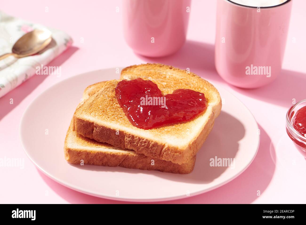 Toast with heart shaped strawberry jam on it as a concept for love and Valentines Day Stock