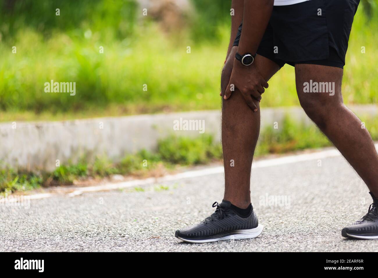 sport runner black man wear watch hands joint hold knee pain Stock Photo