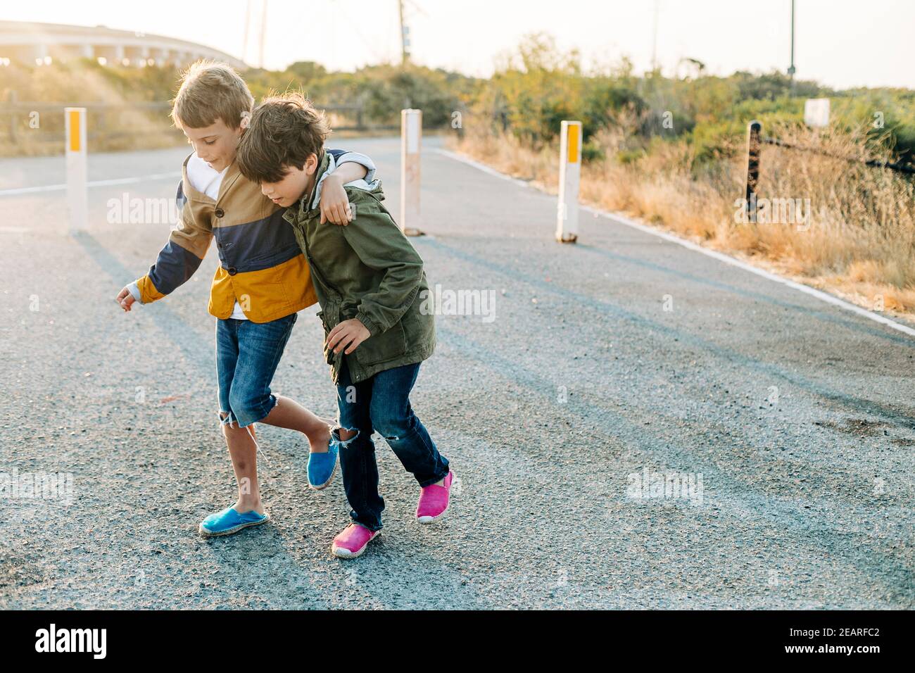 Pre-teens helping to walk by entrance park at sunrise Stock Photo
