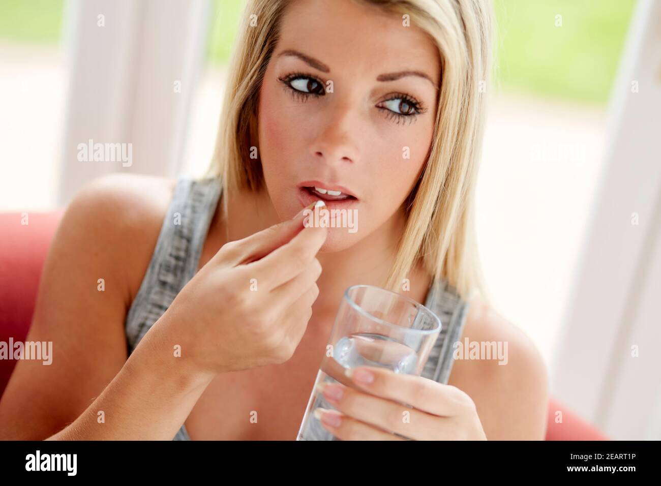 Woman taking tablet with glass of water Stock Photo