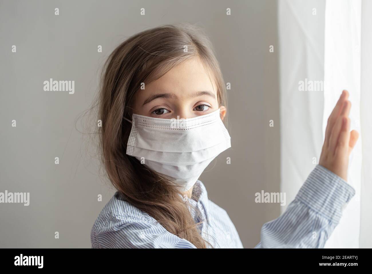 A cute little girl in a disposable protective mask from the coronavirus. Childhood concept
