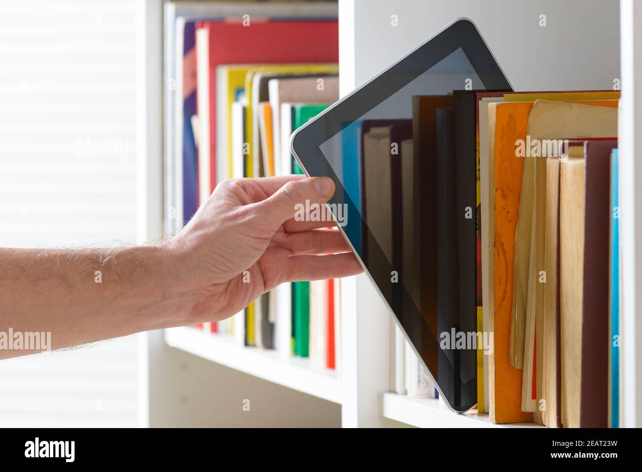 Man taking modern ebook reader from a bookshelf Stock Photo Alamy
