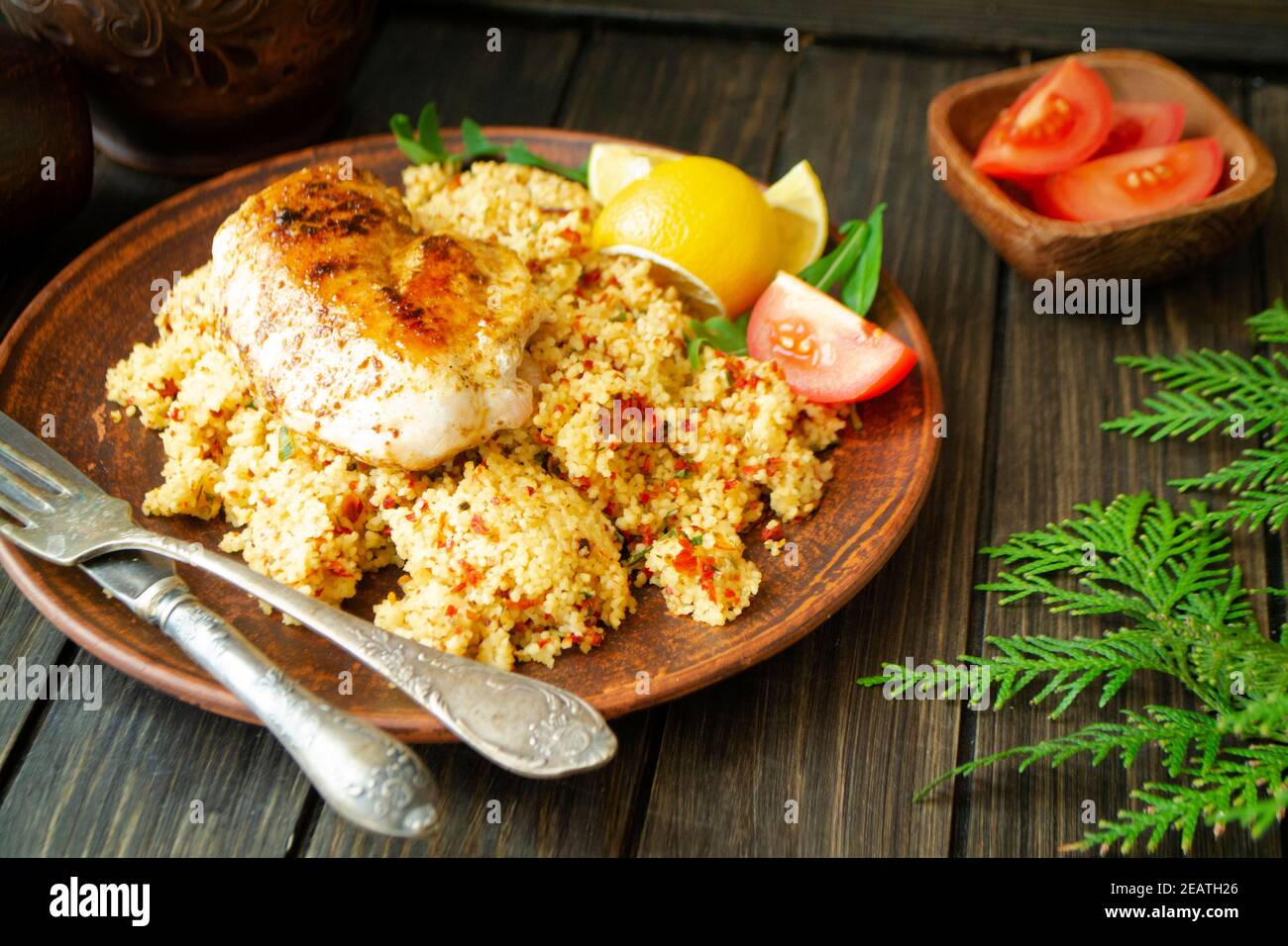 Cous Cous, chicken and vegetables on dark wooden table Stock Photo